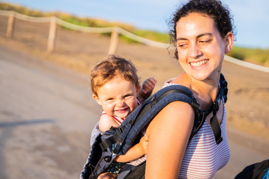 Mãe feliz carregando o bebê no canguru